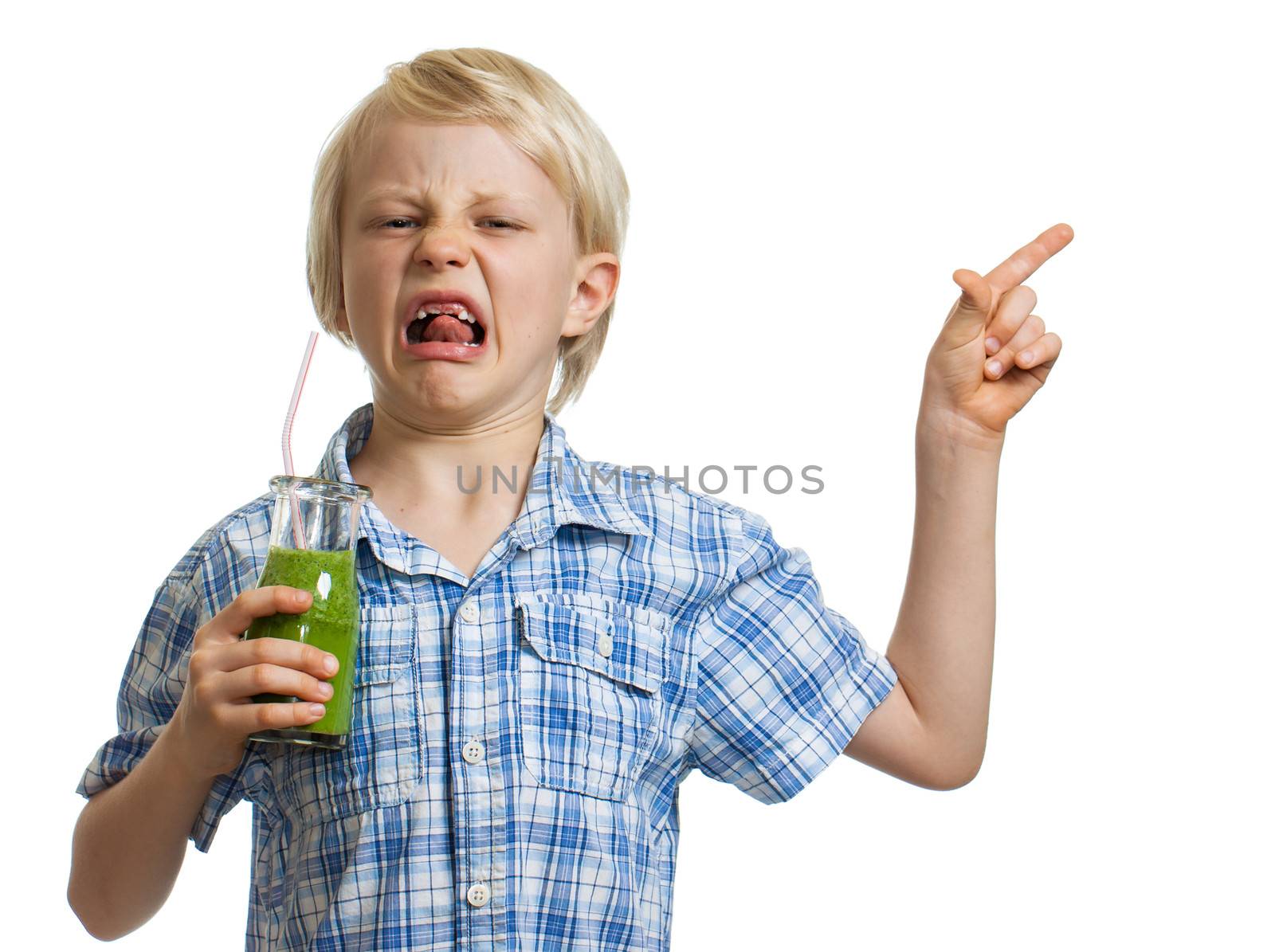 A disgusted boy holding a healthy green smoothy pointing at copy-space. Isolated on white.