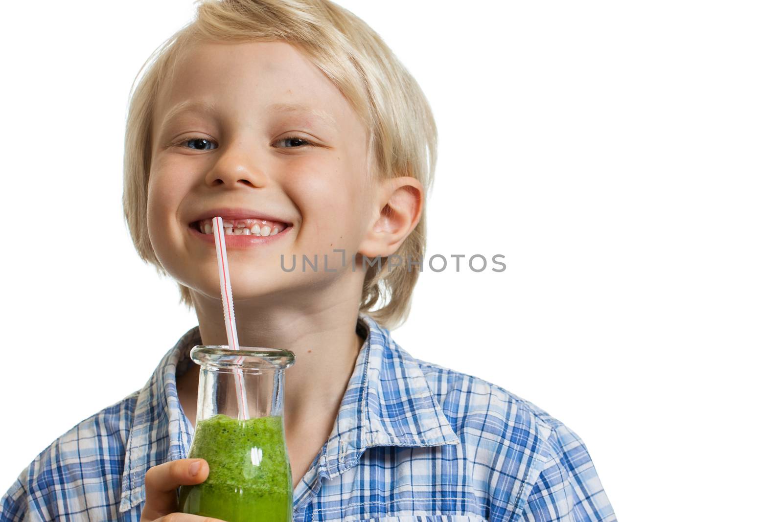 A smiling cute young boy drinking a green smoothie from a straw. Isolated on white.