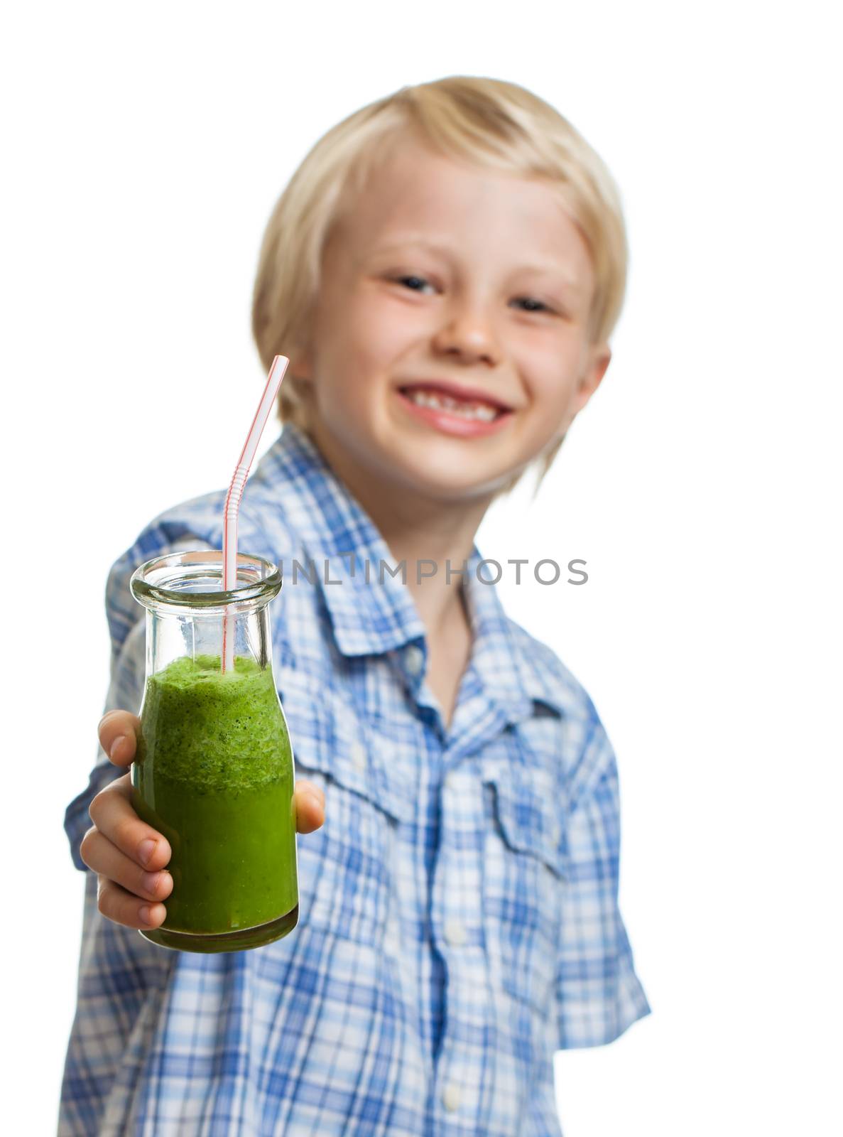 A cute healthy young boy holding a green smoothie or juice smiling. Focus on smoothie.  Isolated on white.