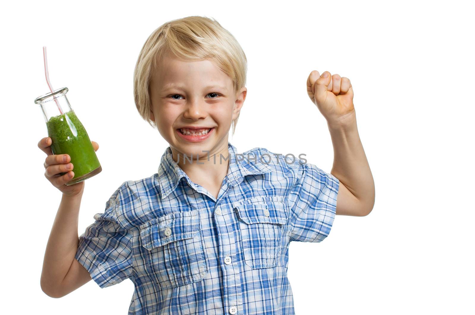 A cute boy holding a bottle of green smoothie or juice is flexing his muscles and smiling. Isolated on white.