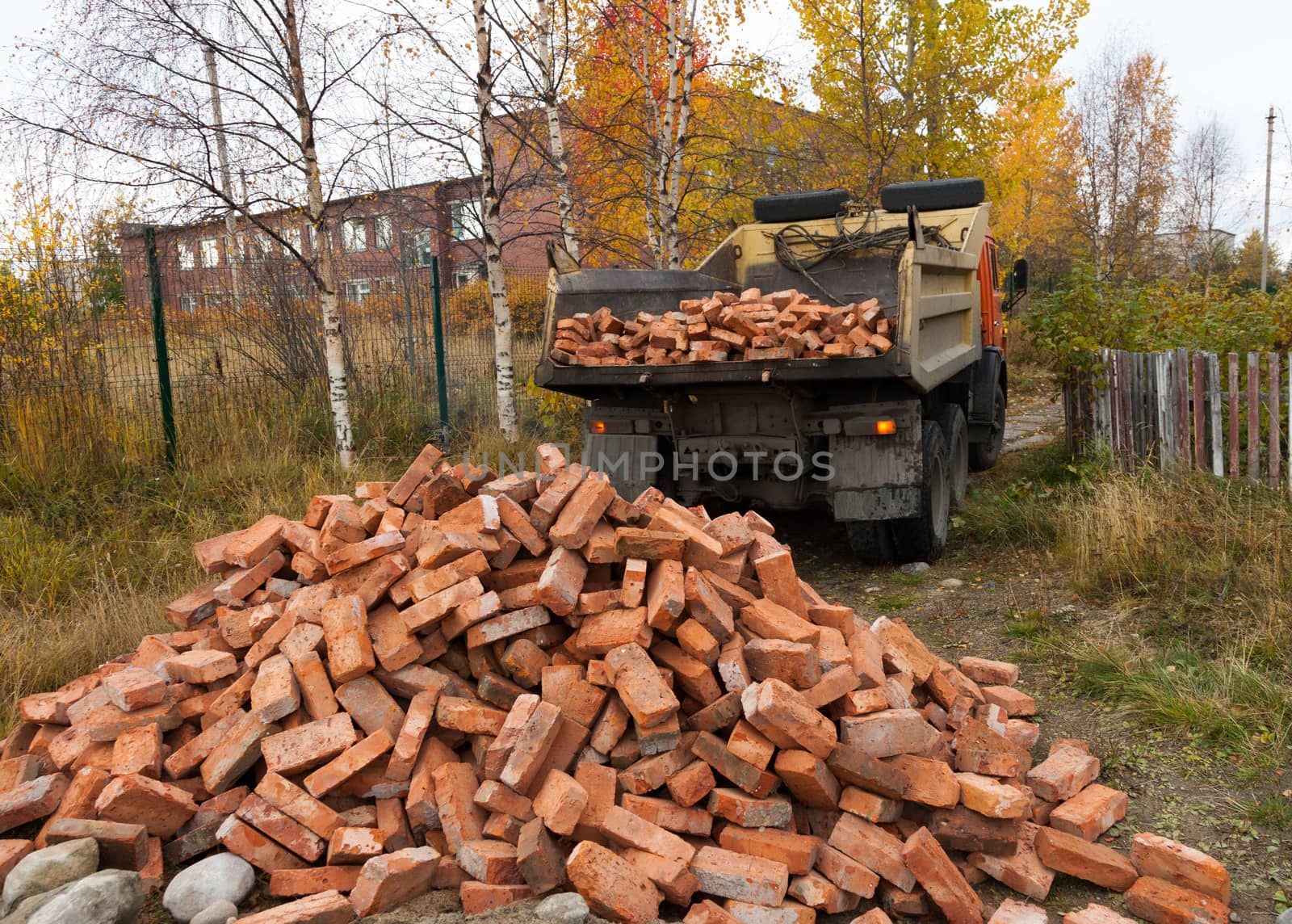 Tipper brought  a lot of red bricks for construction