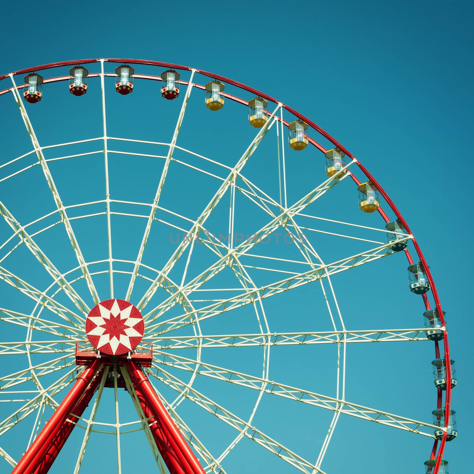 Ferris wheel attraction on blue sky background.