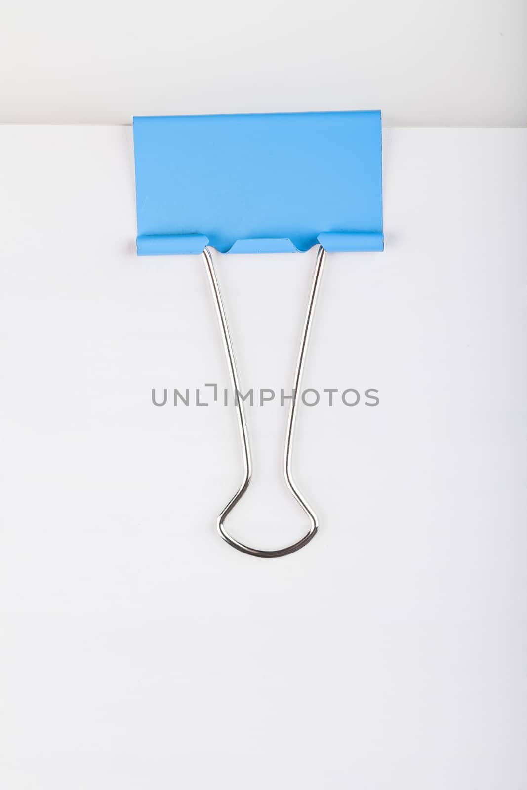 Macro view of blue paper clip on a bunch of paper sheets