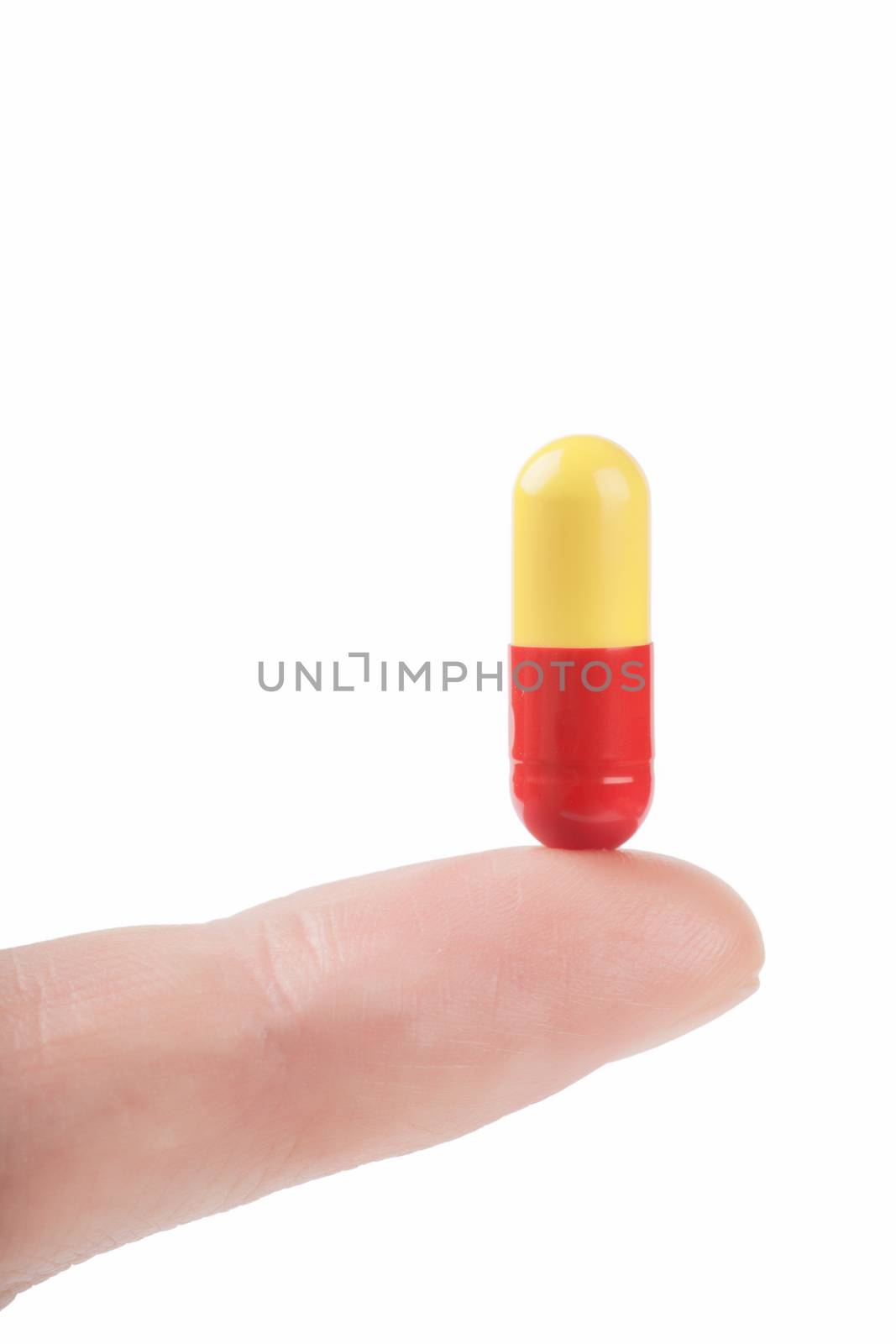 Closeup view of capsule pill on a finger isolated over white background