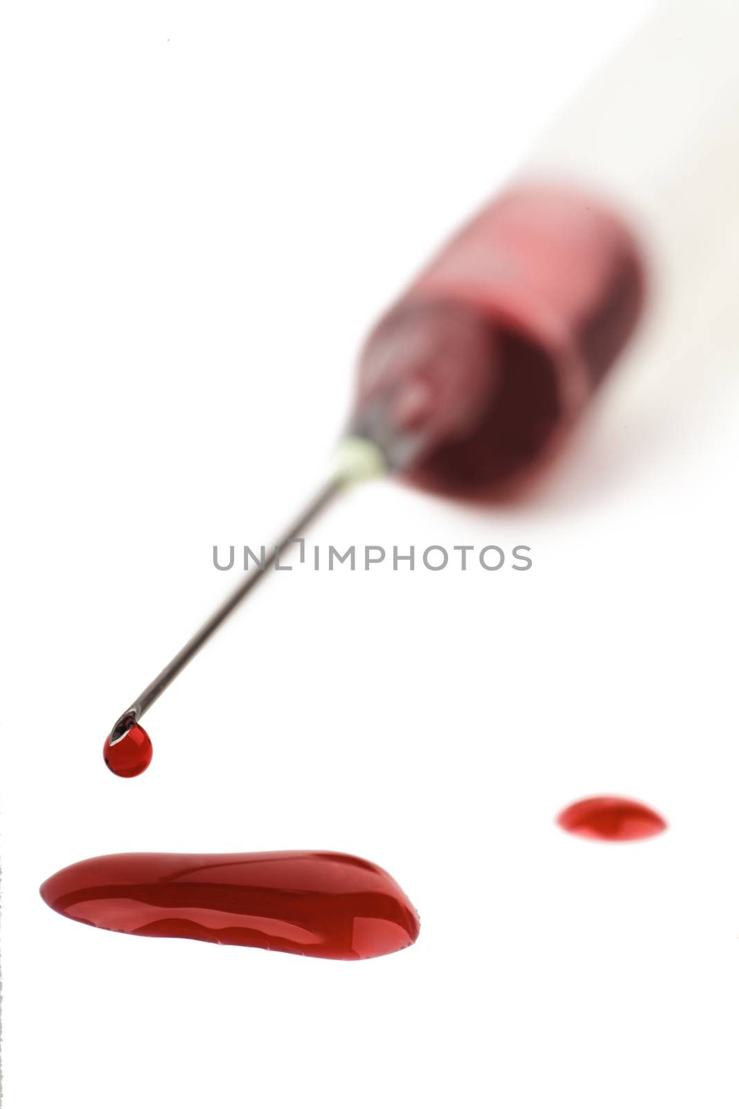 Macro view of drop of blood from syringe over white background