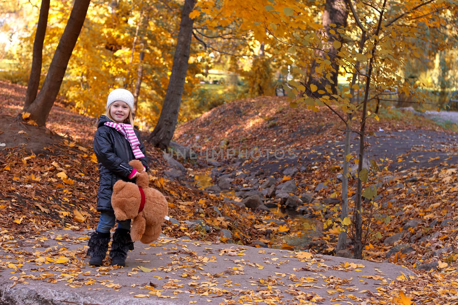 Adorable girl with teddy bear outdoors on beautiful autumn day