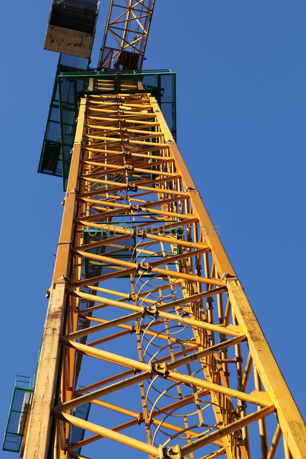 part of yellow construction crane against blue sky, industrial element