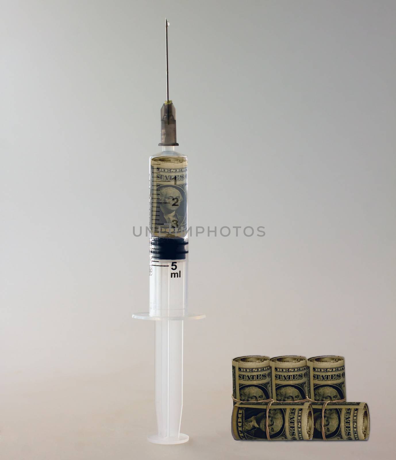 Syringe full of dollars with other rolls of money