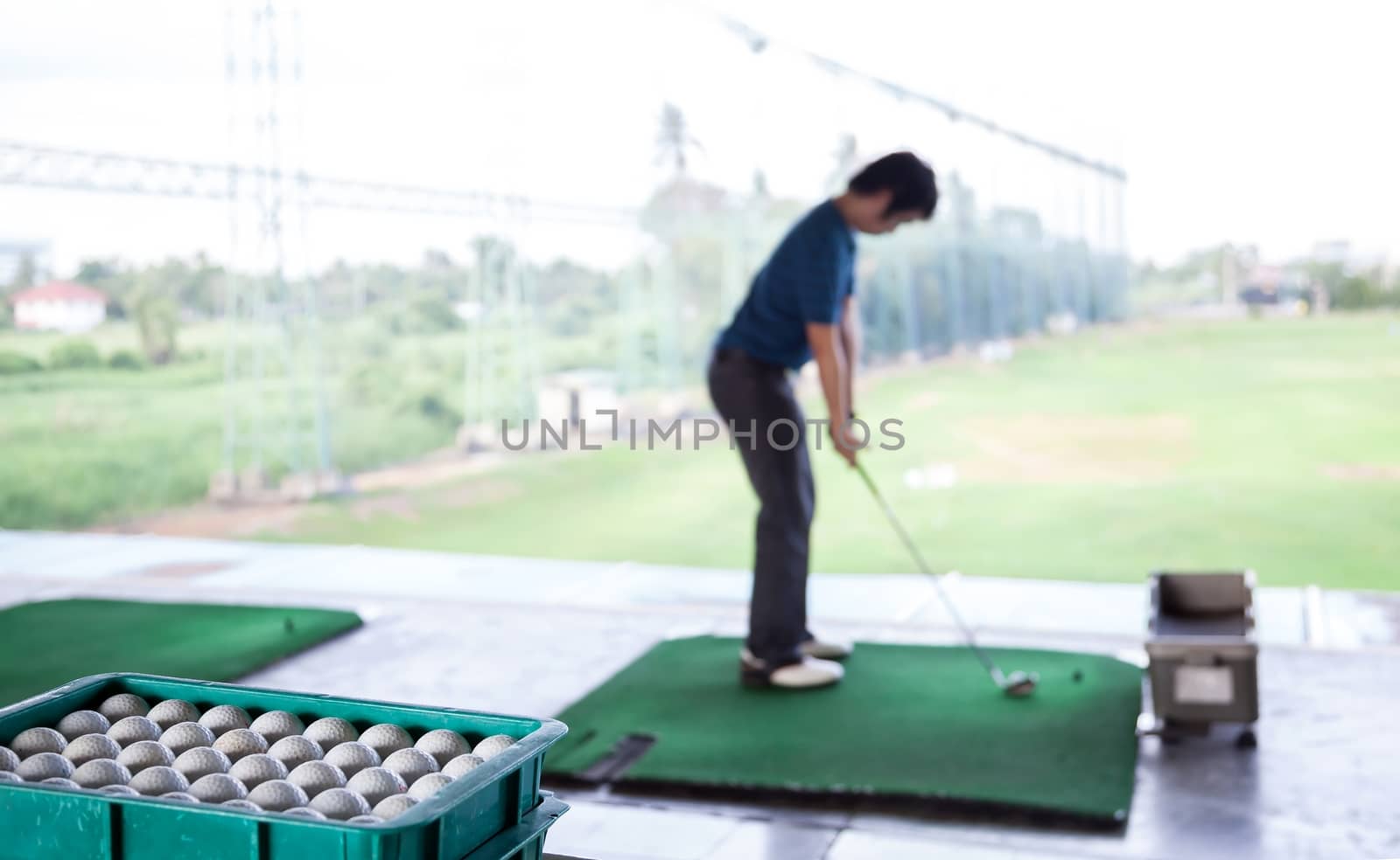 Young male golfer practicing his drive (Selective Focus at Golf ball tray)