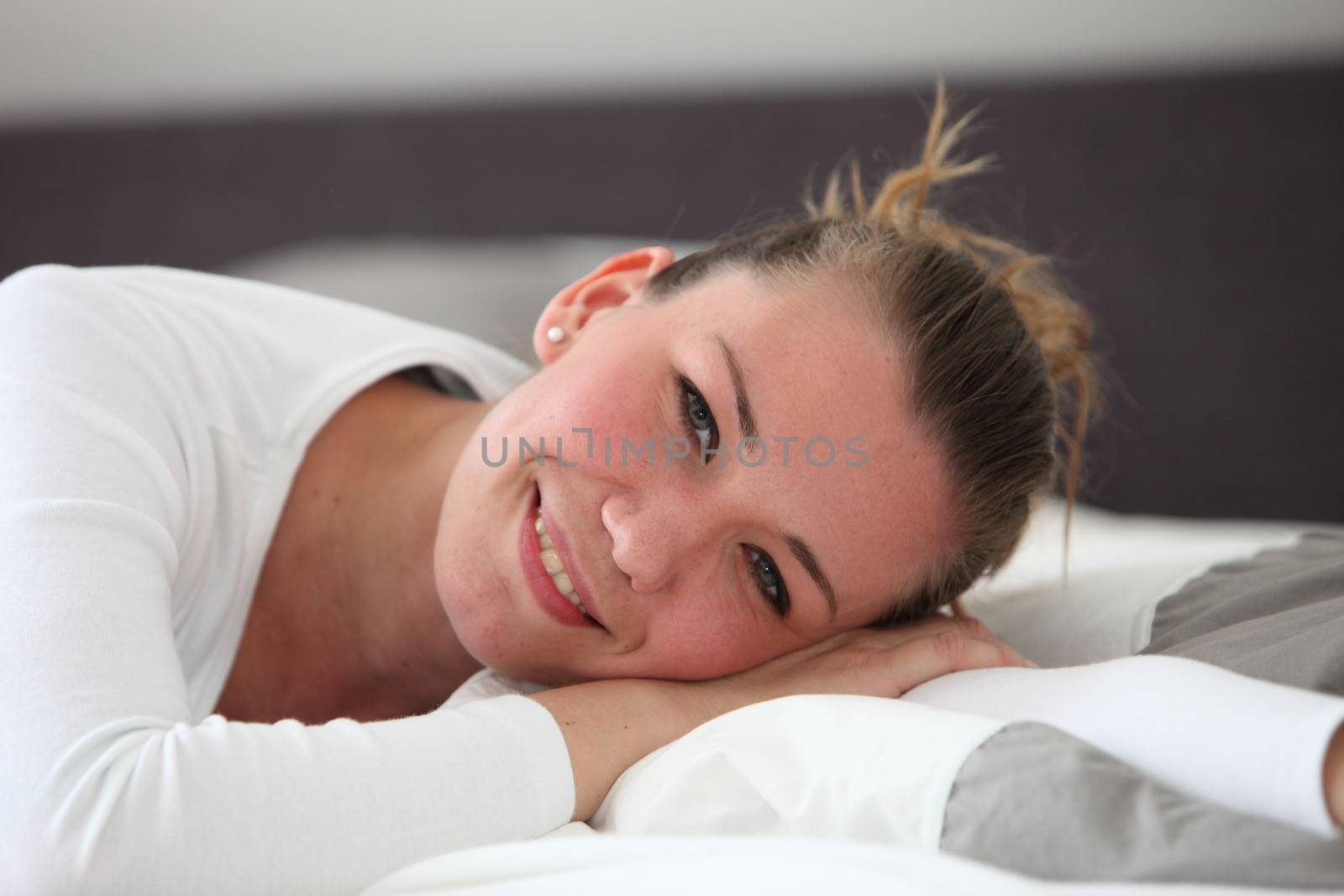 Pretty smiling woman resting on her bed by Farina6000