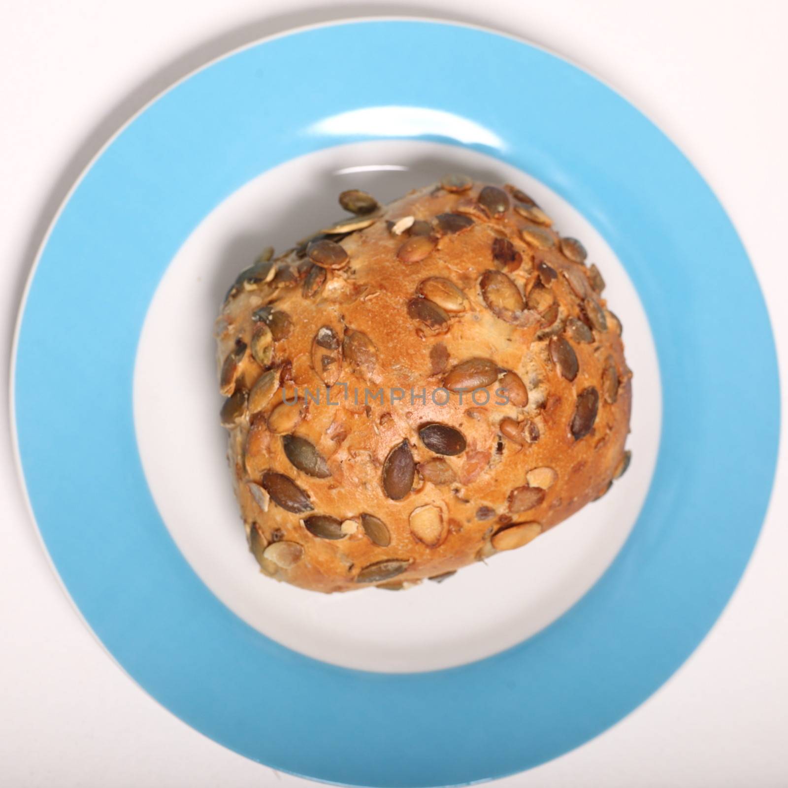 Overhead view of a golden crusty fresh sunflower seed roll served on a plate with a blue border for a tasty snack or as an accompaniment to a meal