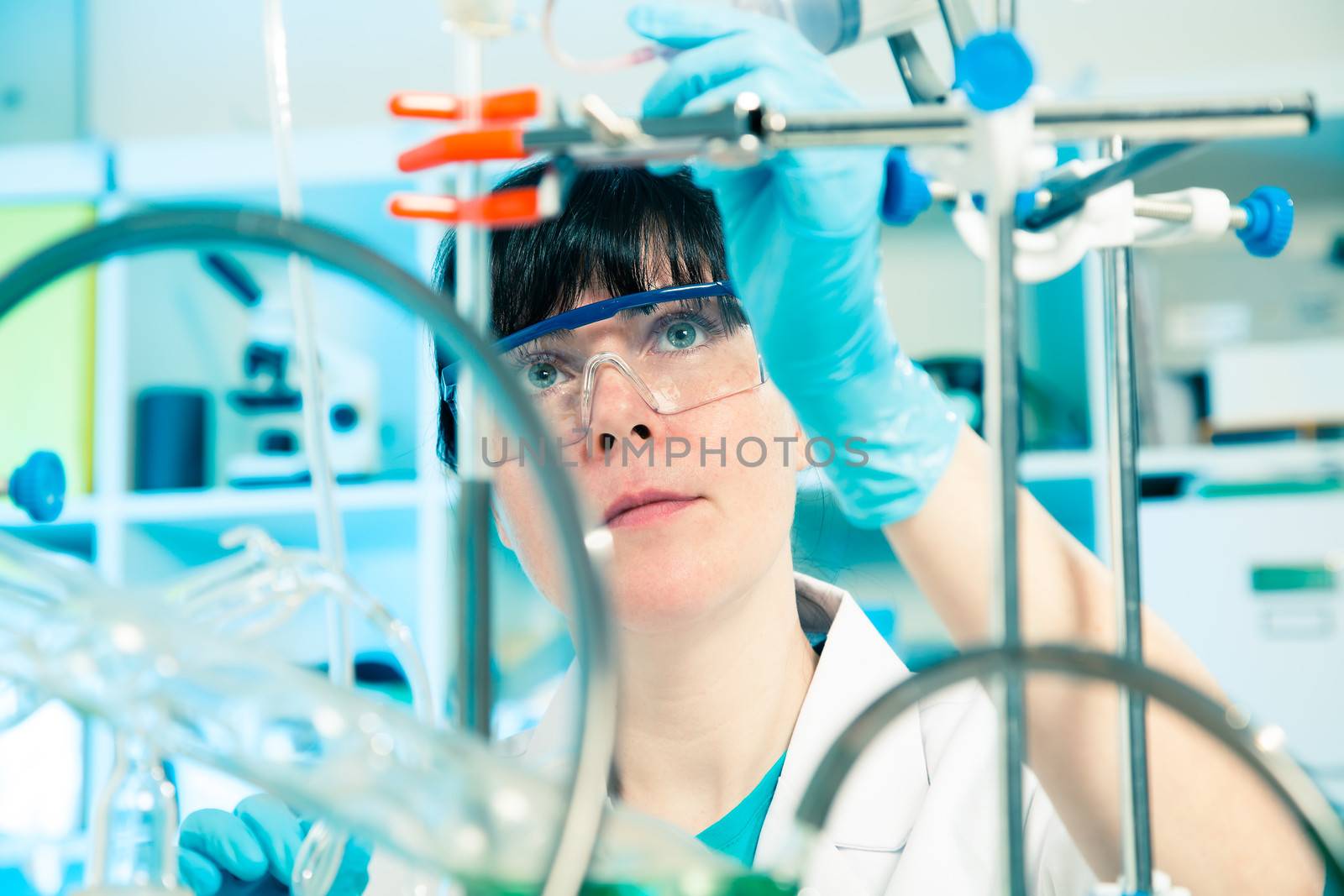 Scientific researcher holding at a liquid solution in a lab  by motorolka