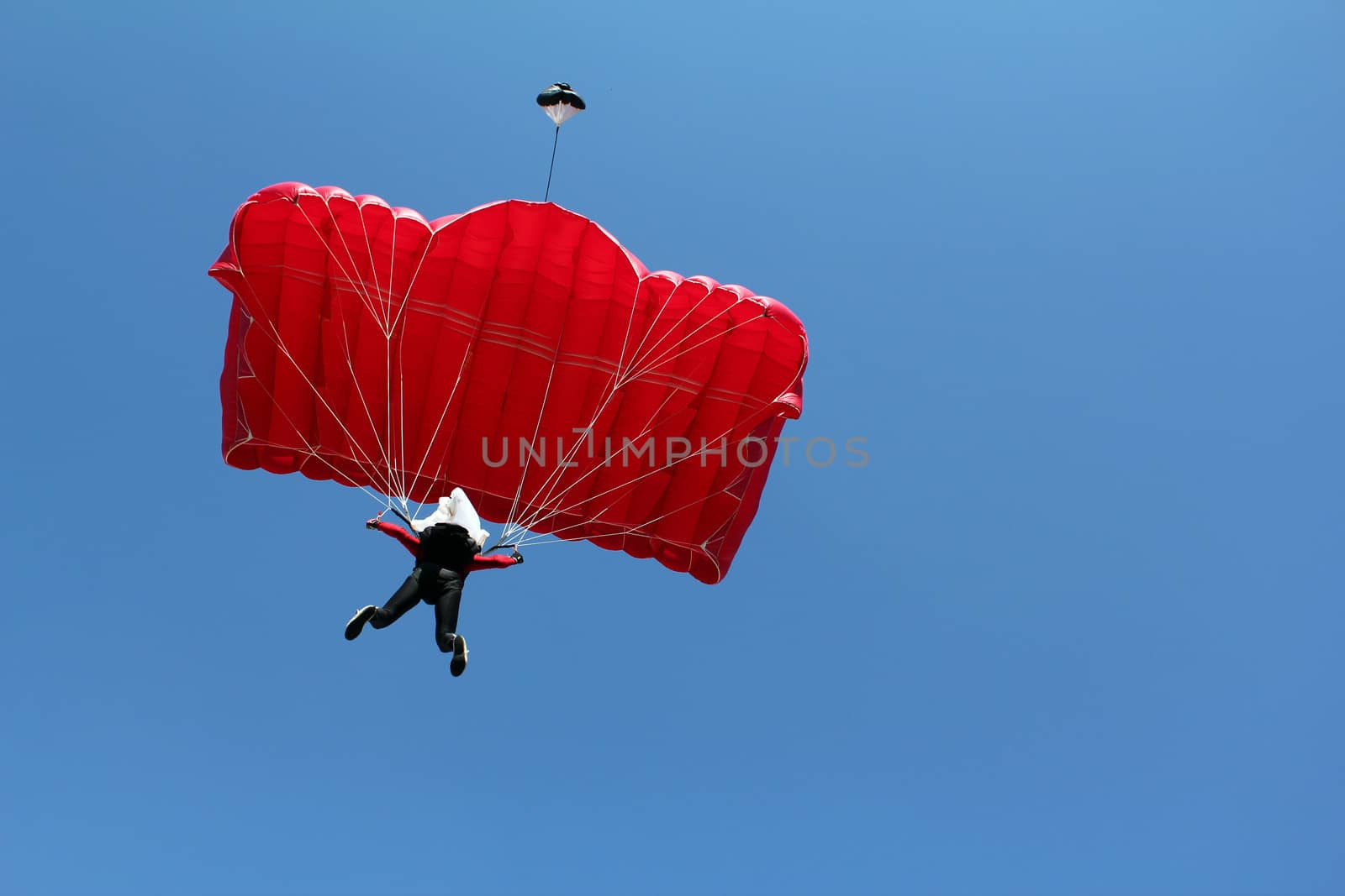 parachutist with red parachute on blue sky by goce