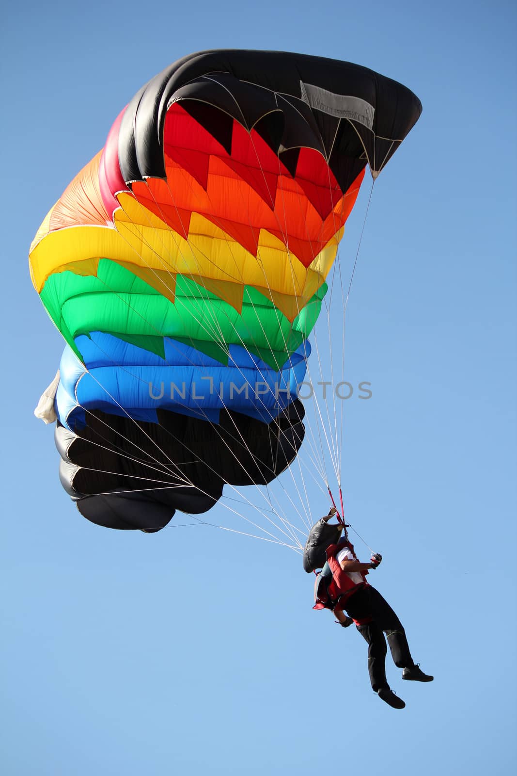 parachutist with colorful parachute on blue sky by goce