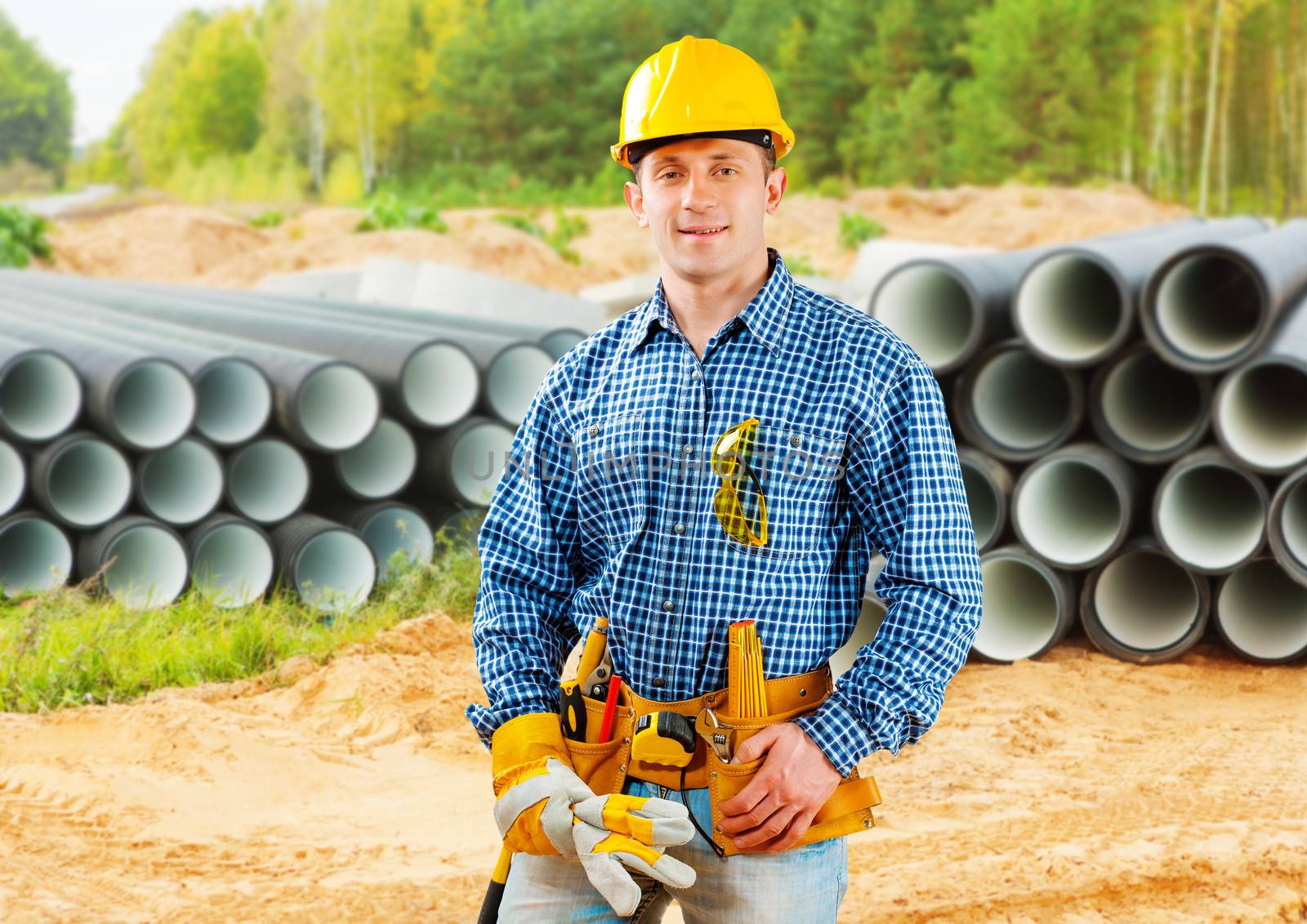 worker near stack of big pipes