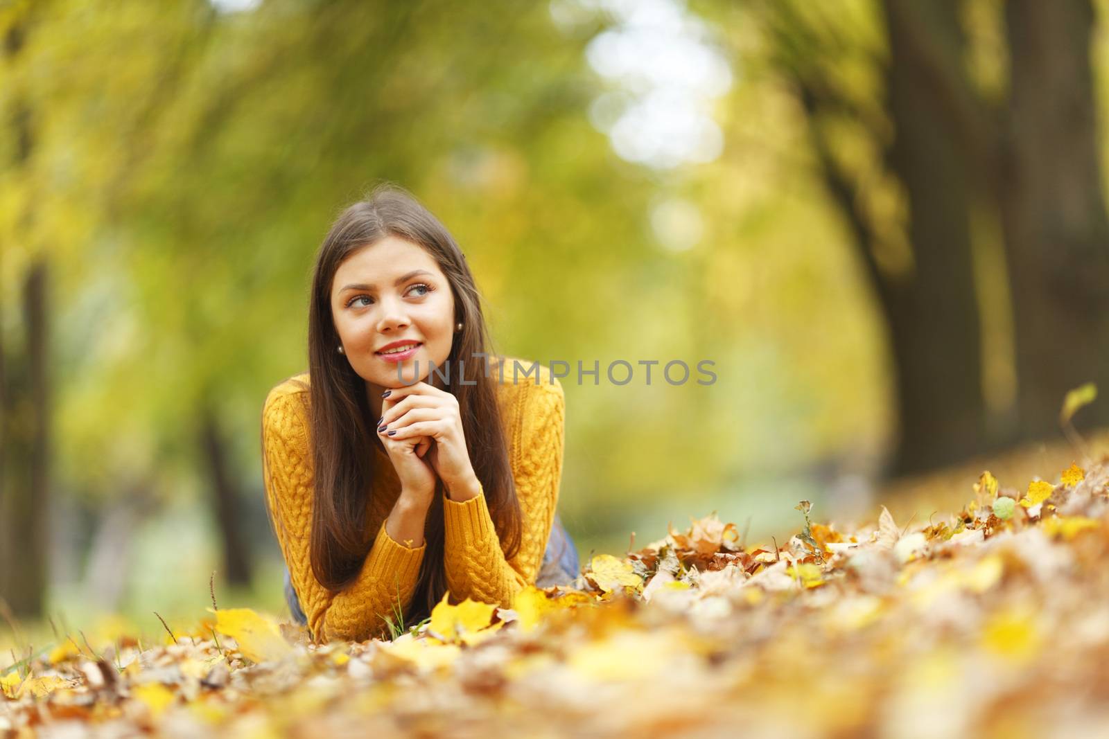 Girl laying on leafs in the autumn park