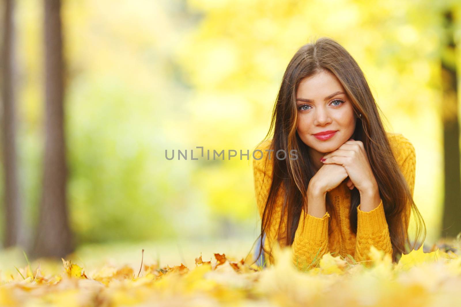 Girl laying on leafs in the autumn park