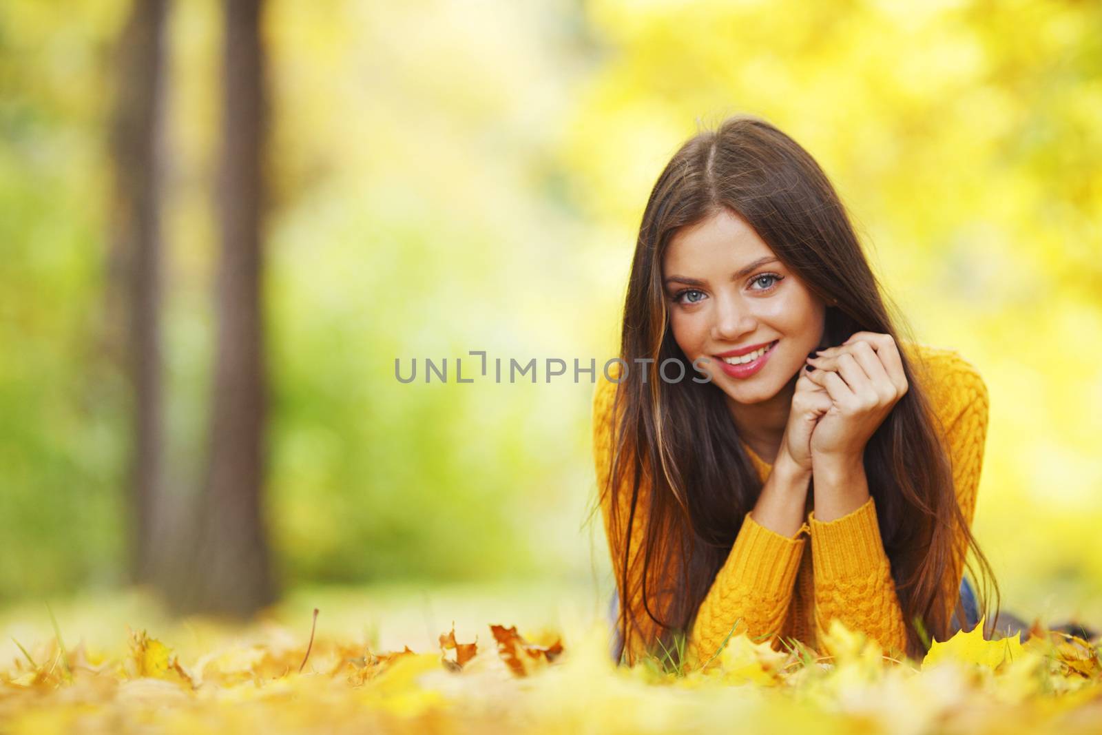 Girl laying on leafs in the autumn park