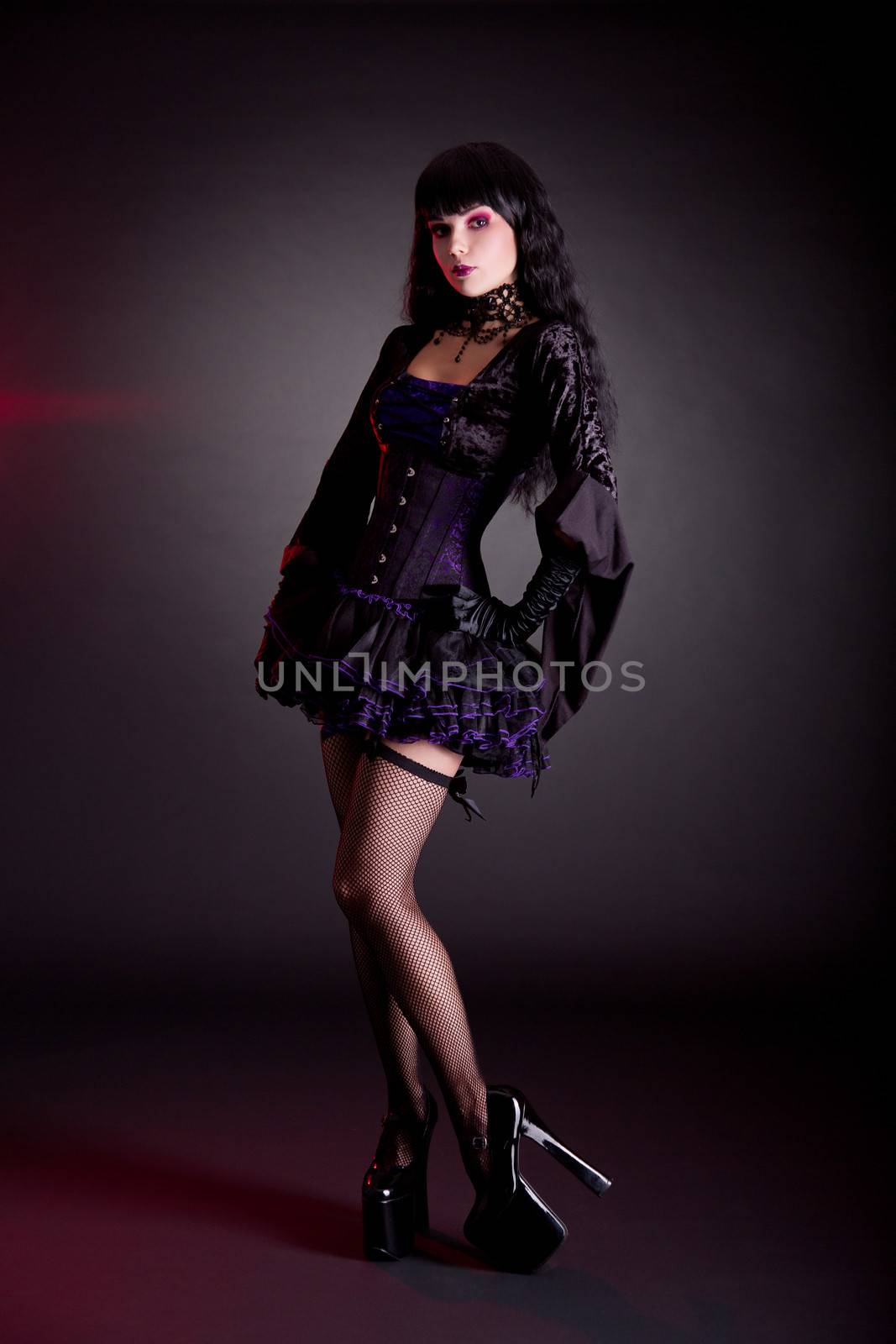 Pretty young woman in Victorian purple and black Halloween outfit and high heels  