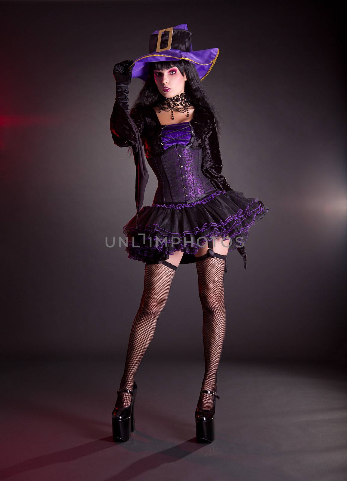 Sexy witch in purple and black fantasy Halloween costume, full length shot  