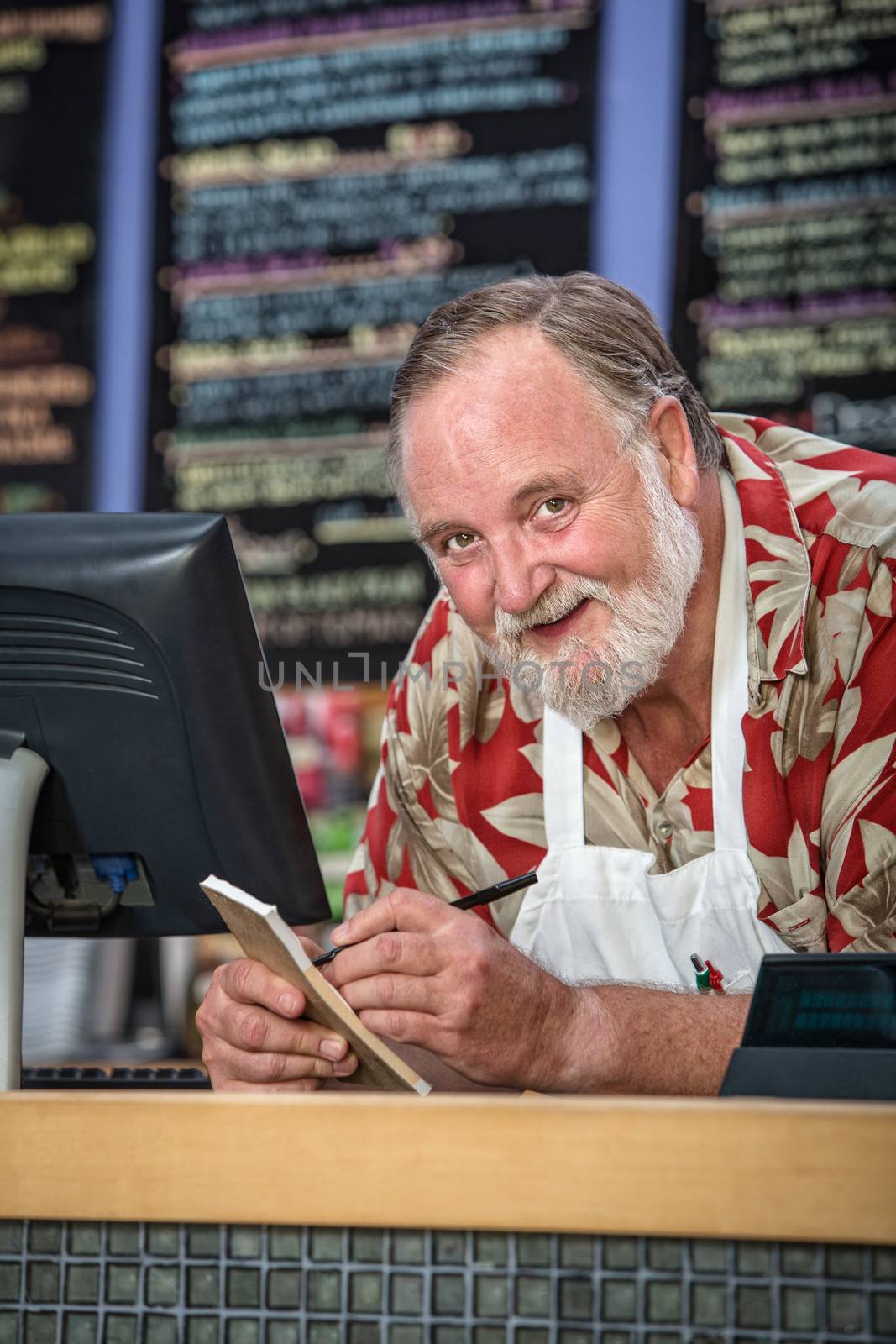 Smiling cafe owner with receipt book behind counter