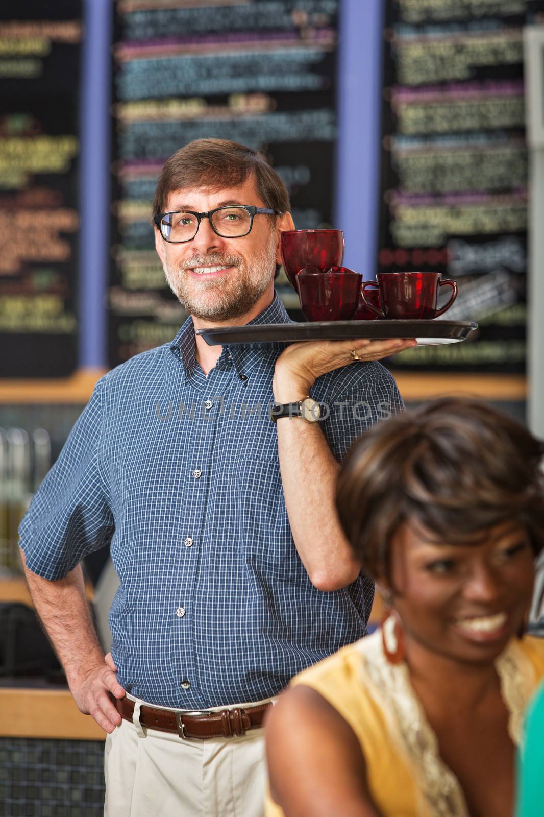 Man with glasses serving drinks to customers