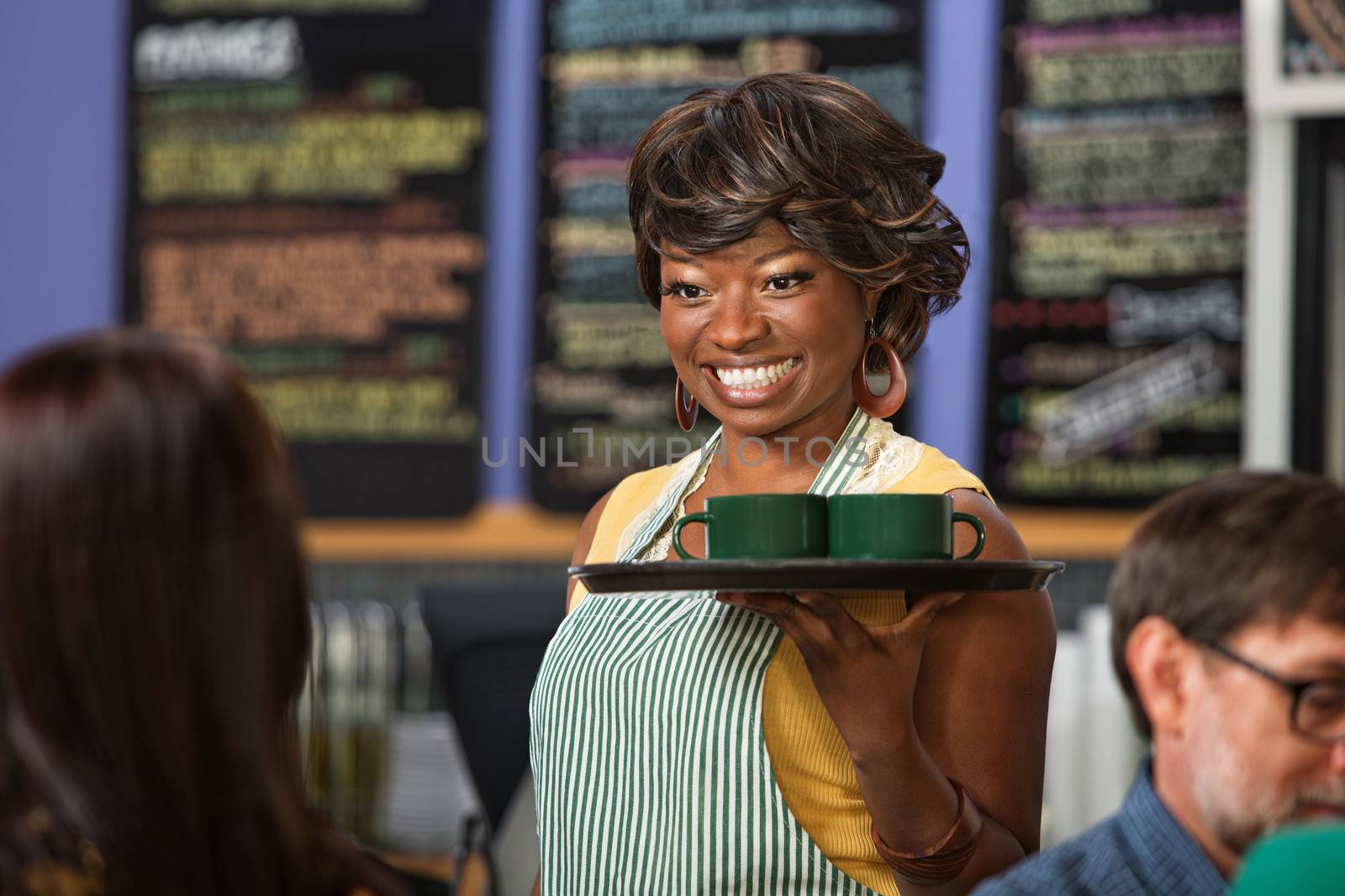 Beautiful Black woman in apron serving drinks on a tray