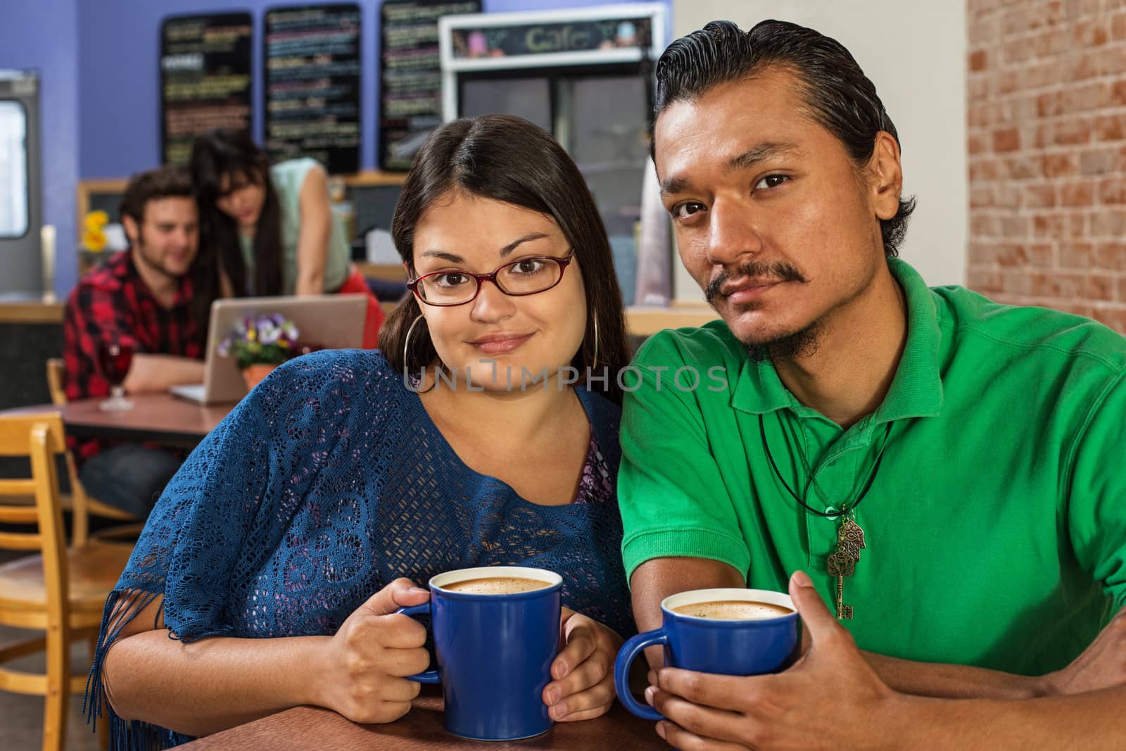 Grinning Latino and Asian couple in cafe