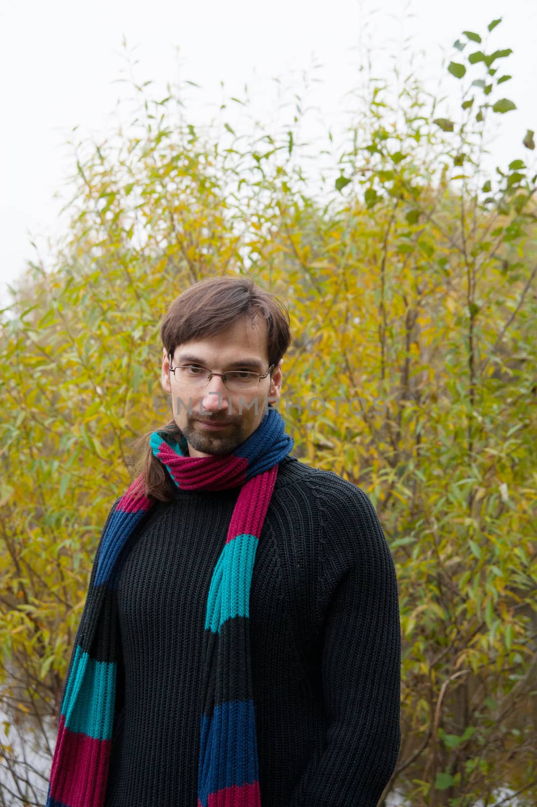 young man with glasses on a background of autumn forest