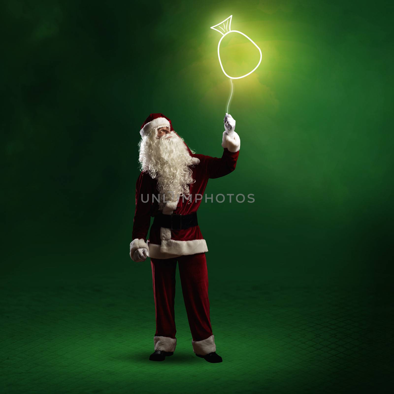 Santa Claus is holding a shining symbol of the bag with gifts on a string