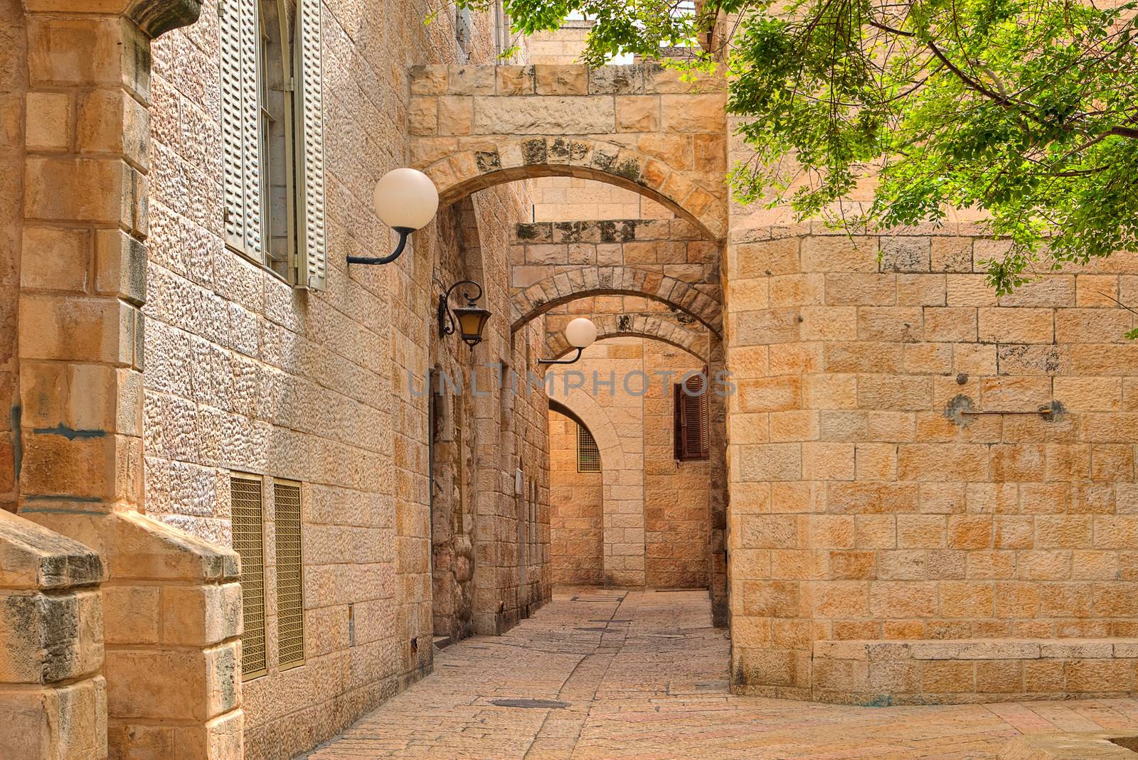 Narrown cobbled street among traditional stoned houses of jewish quarter at old historic part of Jerusalem, Israel.