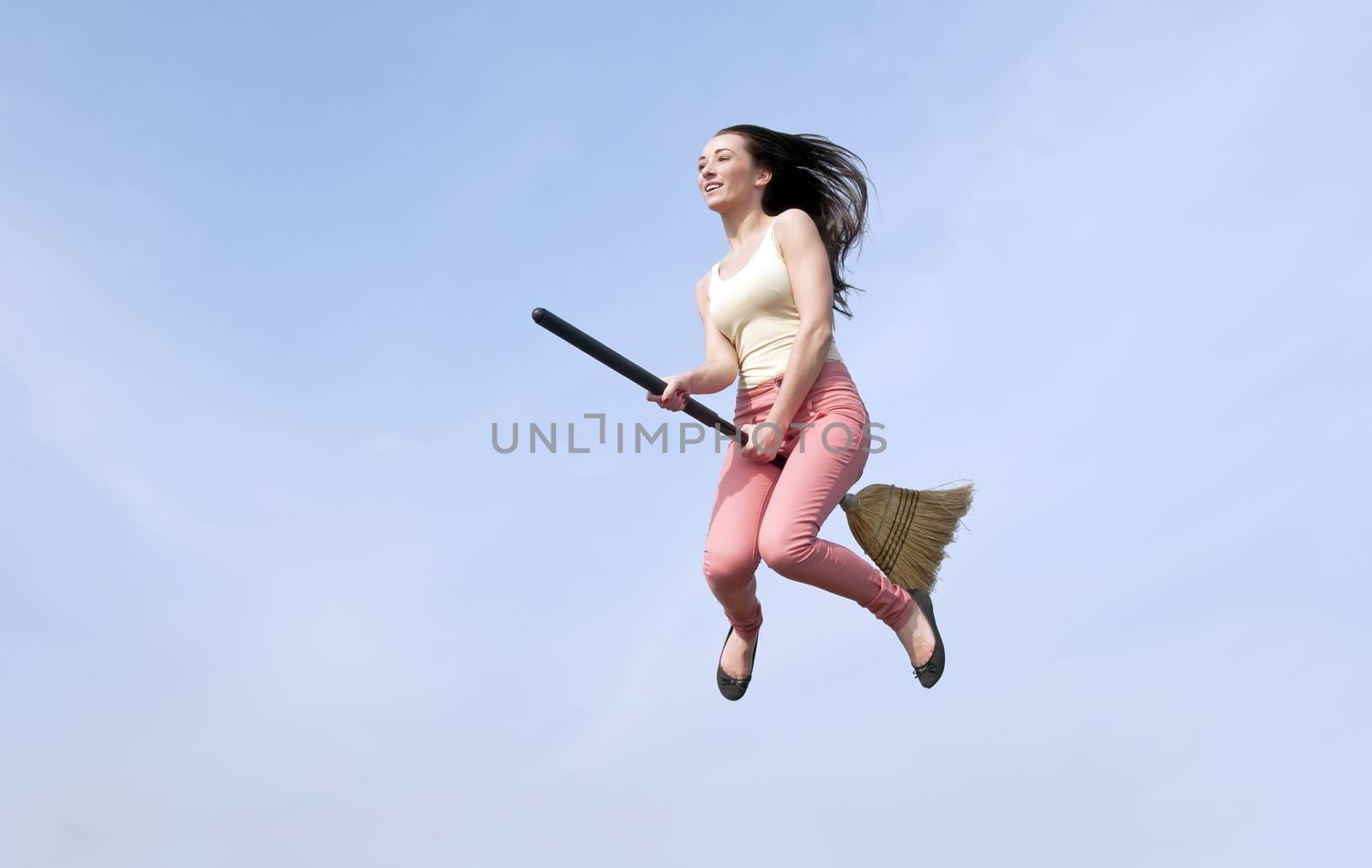 happy young woman flying with a broom