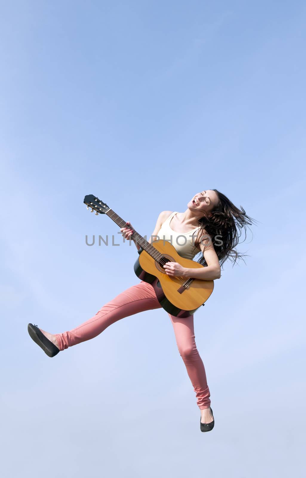 happy young woman jumping with guitar