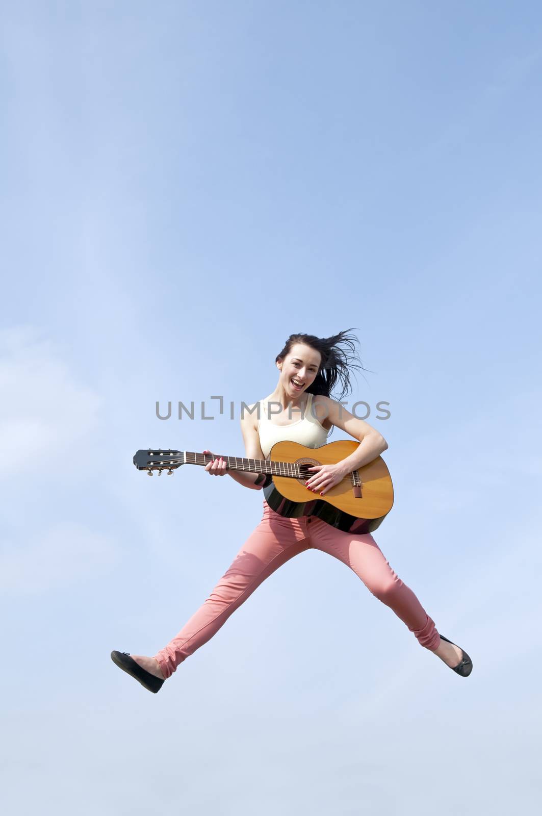happy young woman jumping with guitar