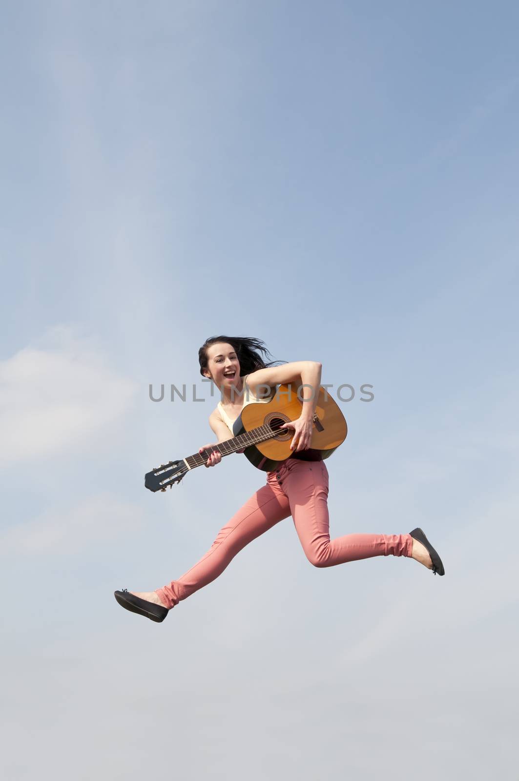 happy young woman jumping with guitar