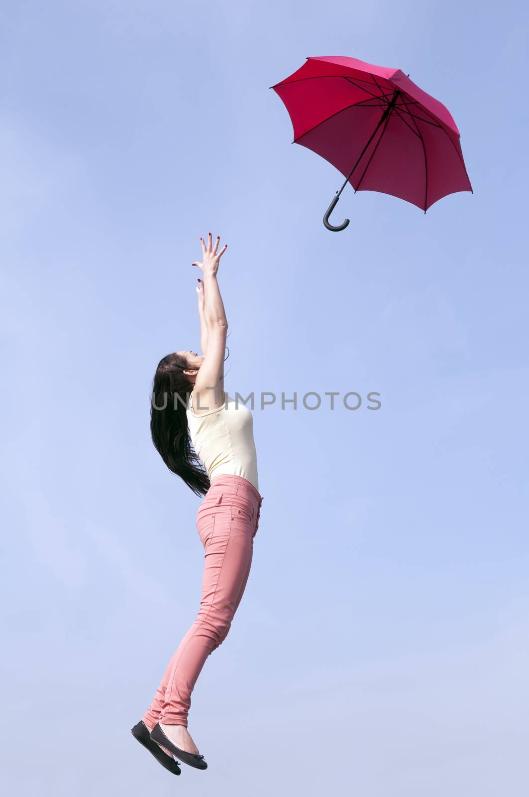 young woman jumping with red umbrella