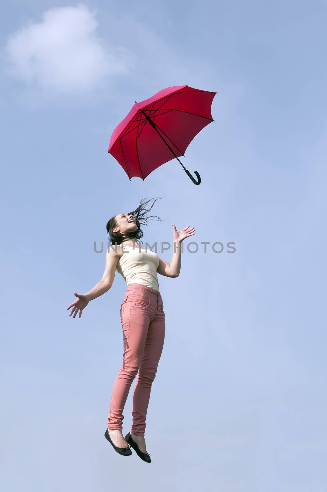young woman jumping with red umbrella