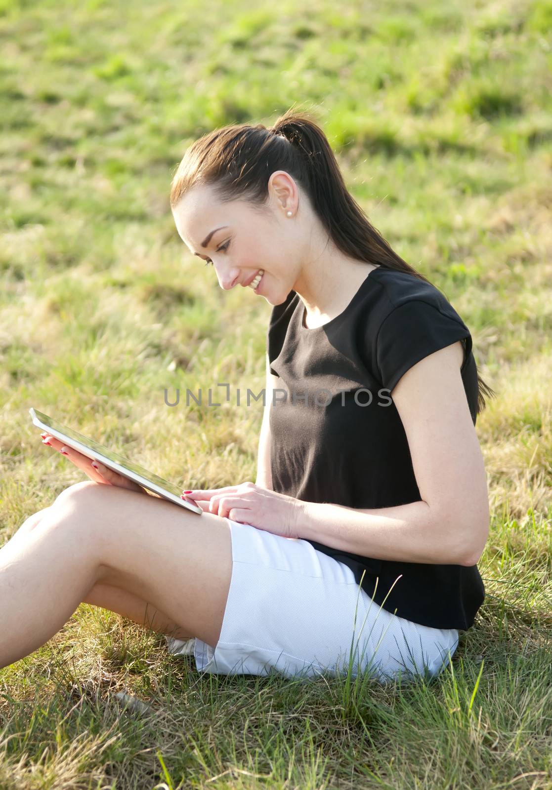 beautiful young woman with digital tablet on a meadow