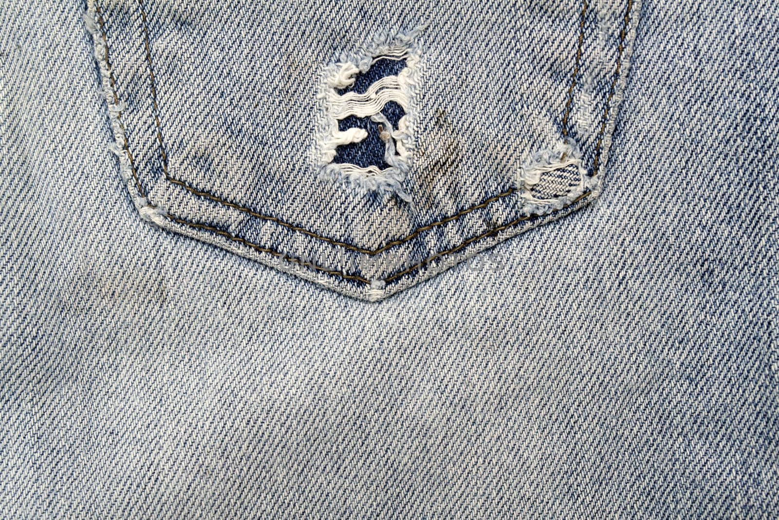 Close up image of denim jeans pocket with a ripped hole