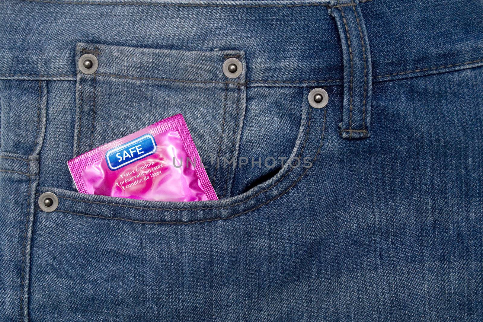 Pink wrapped condom on a demin jean pocket