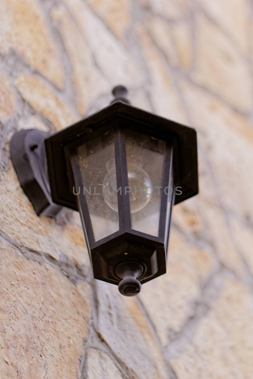 antique black lantern side by building (stone wall)