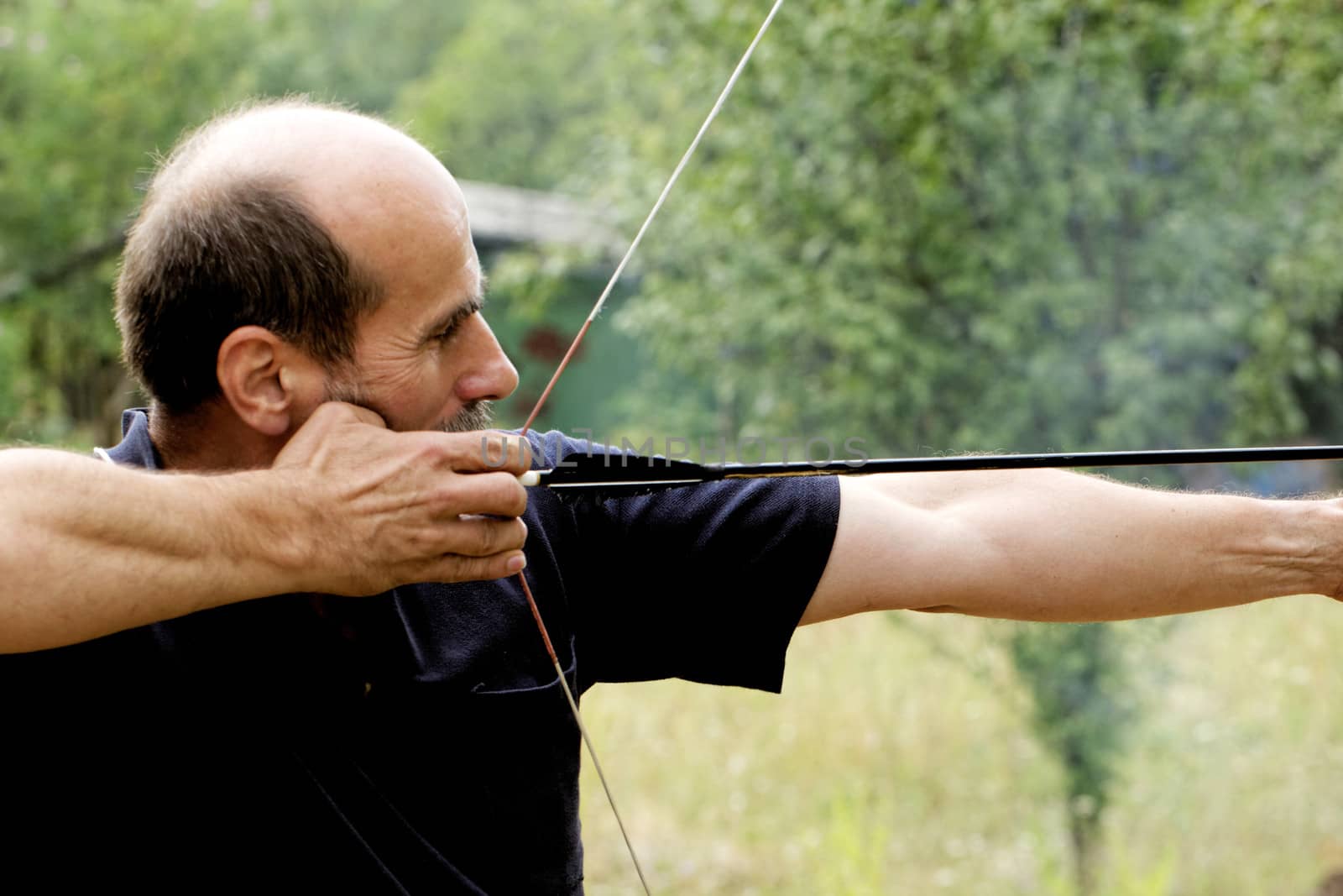 archery man shooting arrow with bow in the nature