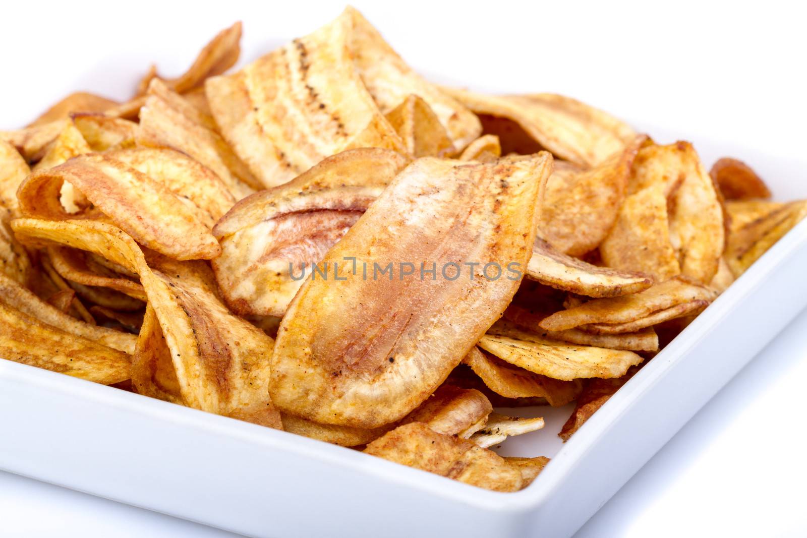 Crispy banana chip on white dish on white background