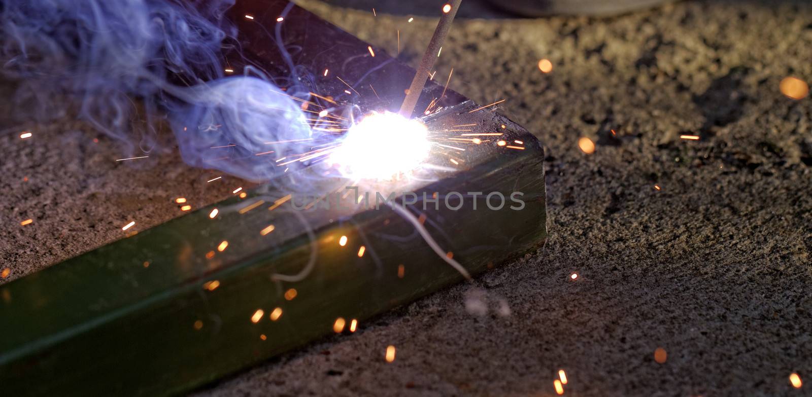 Iron welding with bright light and smoke at manufacturing