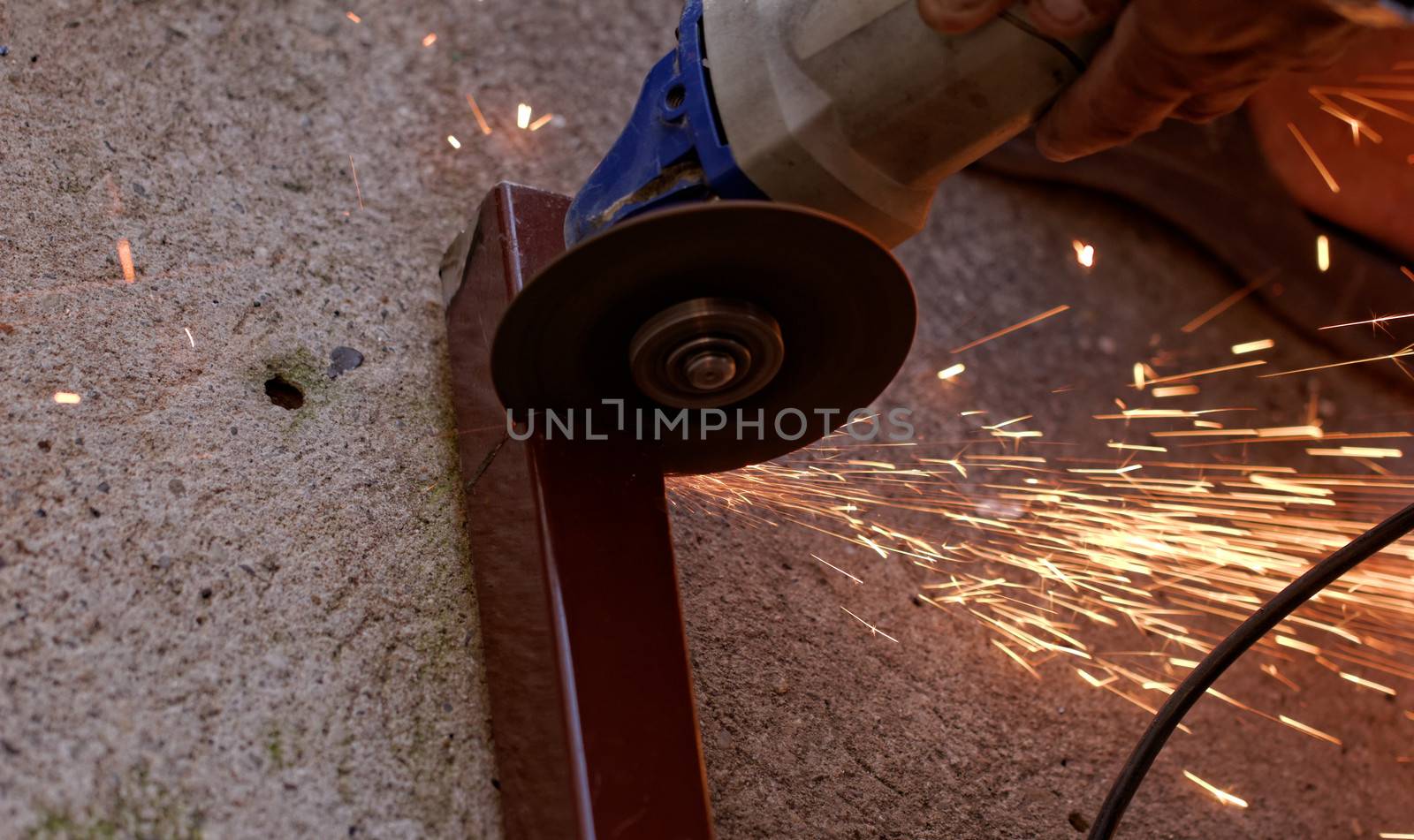 Metal sawing with hand grinder. Sparks while grinding iron.