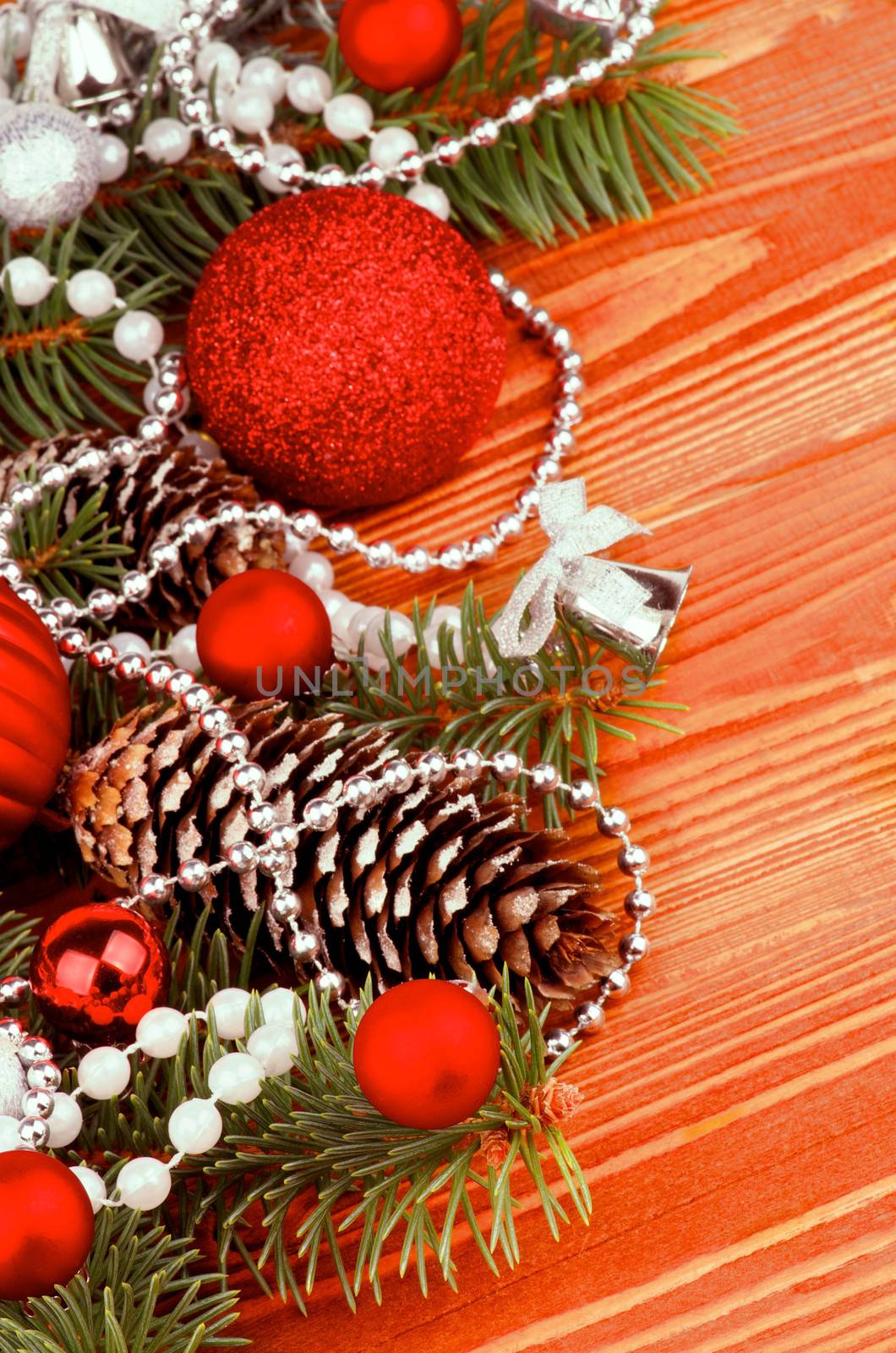 Arrangement of Spruce Branch and Fir Cones with Red and Silver Baubles, Bows,  Pearl and Silver Beads closeup on Wooden background