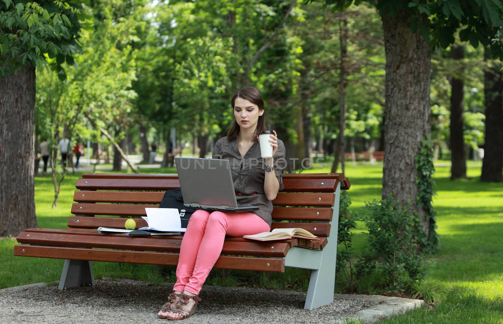Young woman working on a laptop outside in a park.