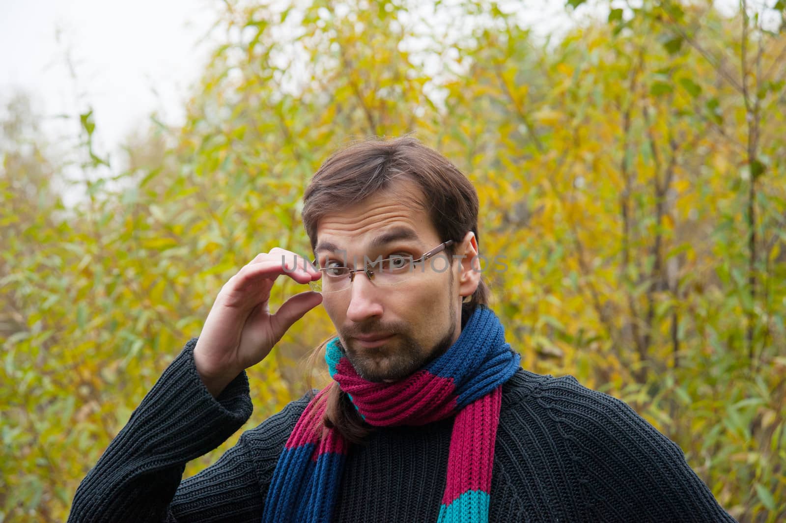 man with glasses on a background of autumn forest