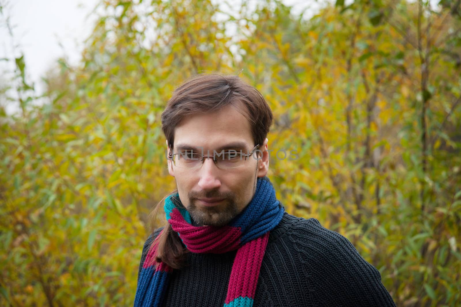 man with glasses on a background of autumn forest