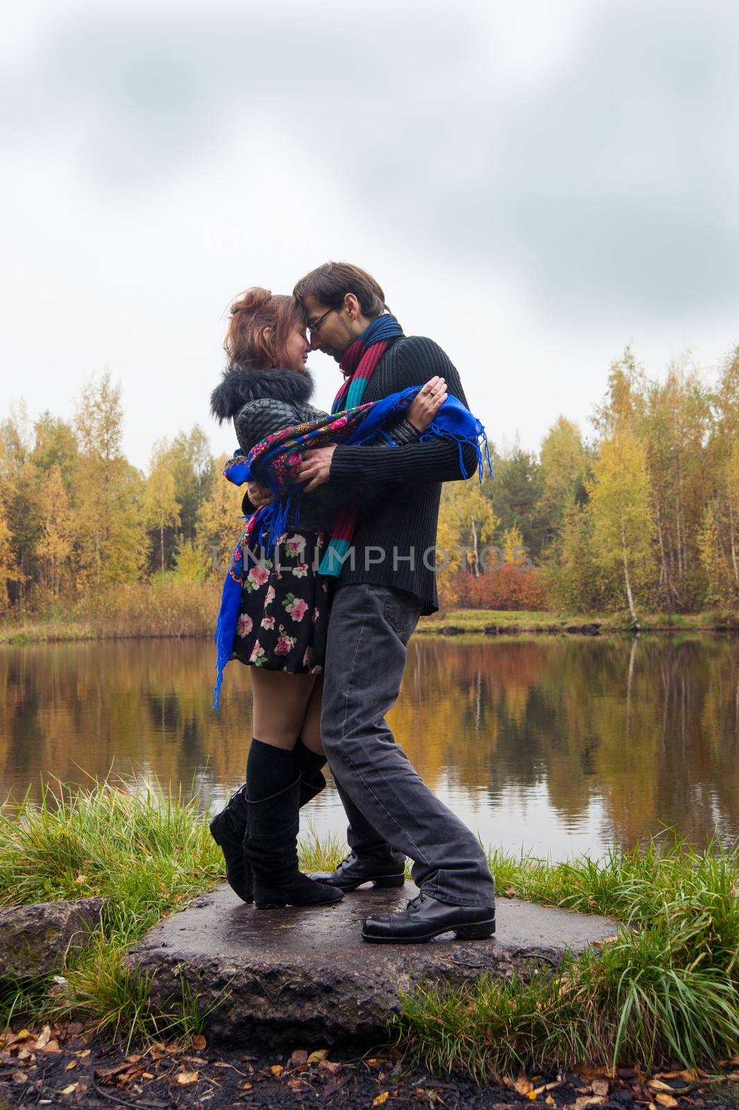 Beautiful loving couple dancing at a lake in autumn